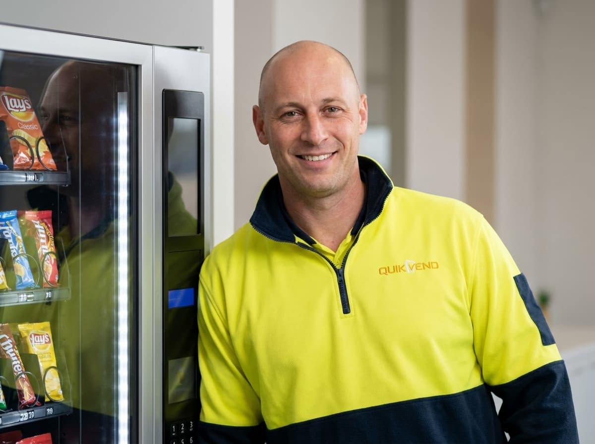 A QuikVend team member beside a QuikVend vending machine in the Riverina